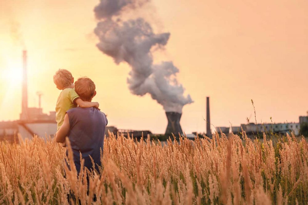 Due bambini in un campo di grano con ciminiere sullo sfondo