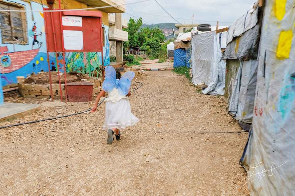 Bambina con ali di farfalla nel campo profughi di Akkar