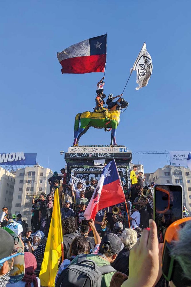 Manifestanti su monumento con bandiere