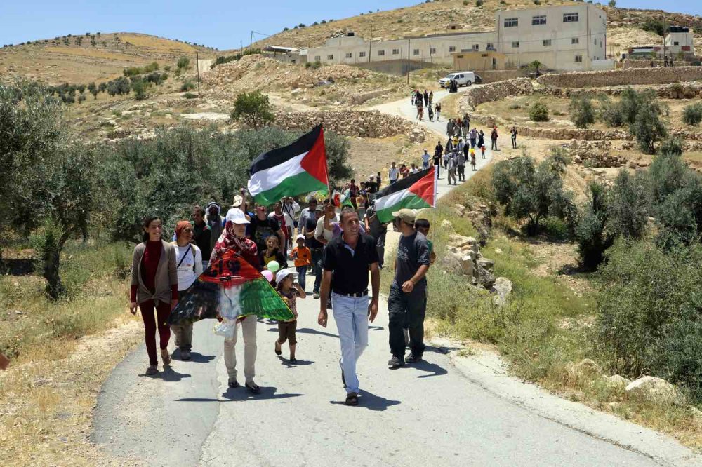 Manifestazione con bandiere palestinesi in un villaggio