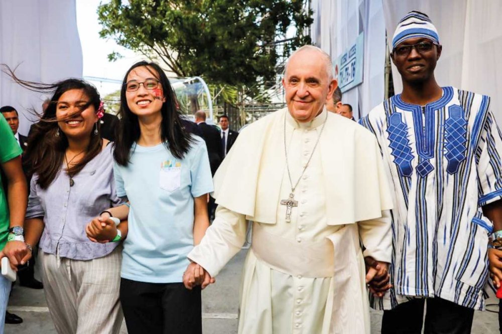 Papa Francesco cammina dando la mano a giovani di diverse nazionalità