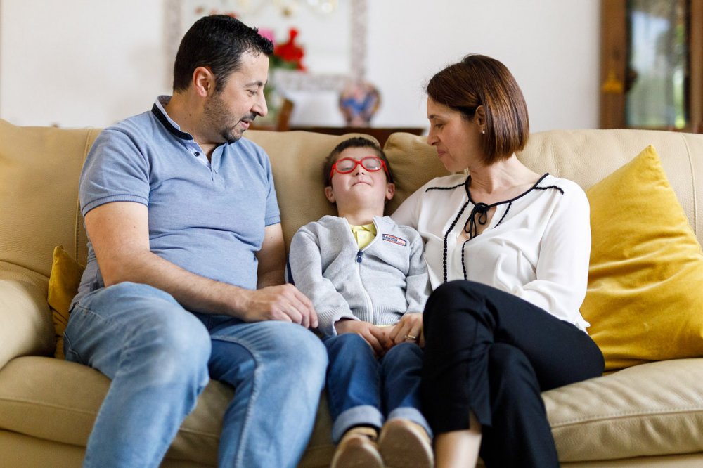 Genitori sorridenti sul divano con bambino