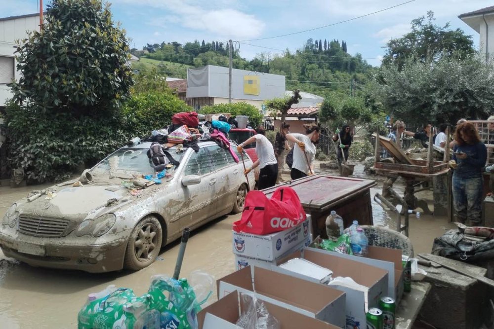 Giovani spalano il fango vicino ad un'auto uscita dal fango