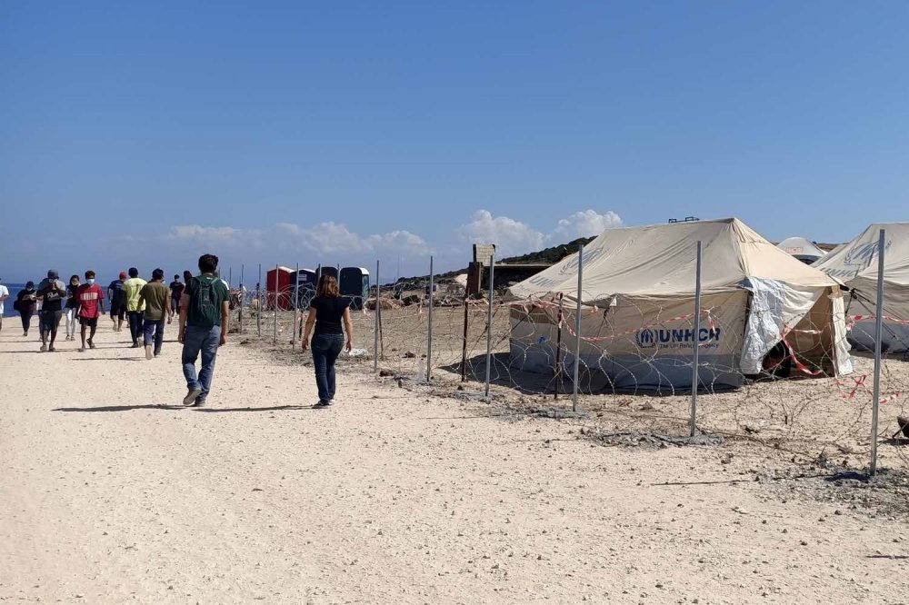 Filo spinato e rete con tende UNHCR attorno al campo profughi