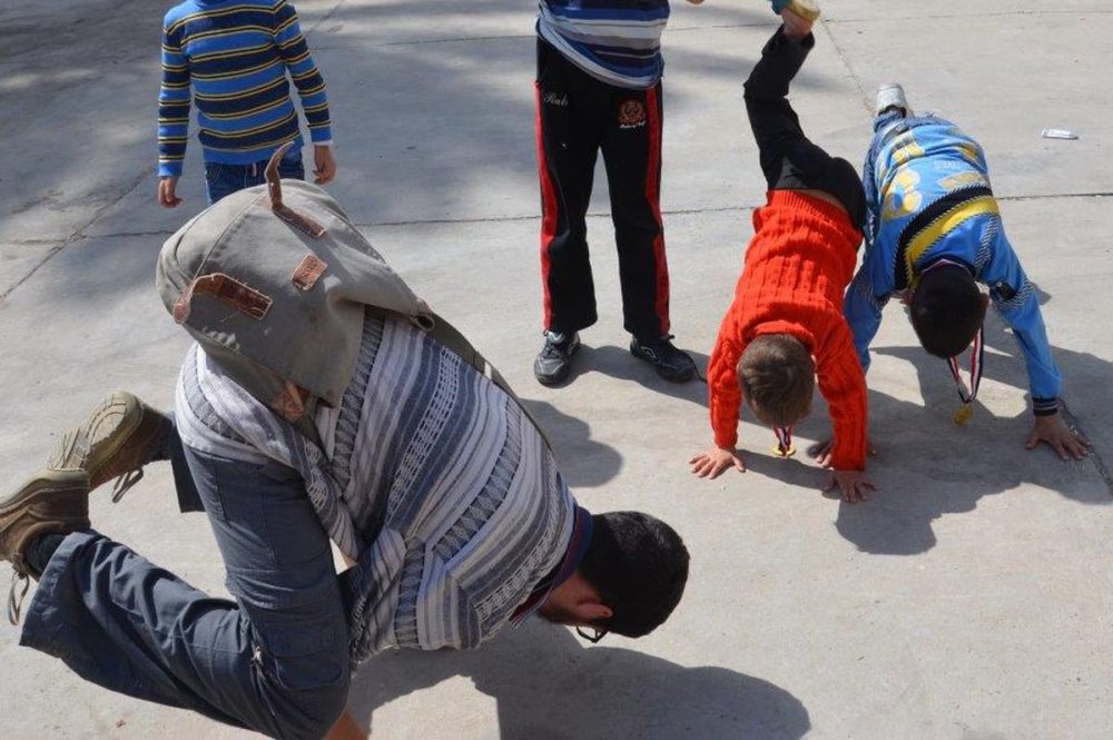 Volontari e bambini fanno le capriole sul cemento