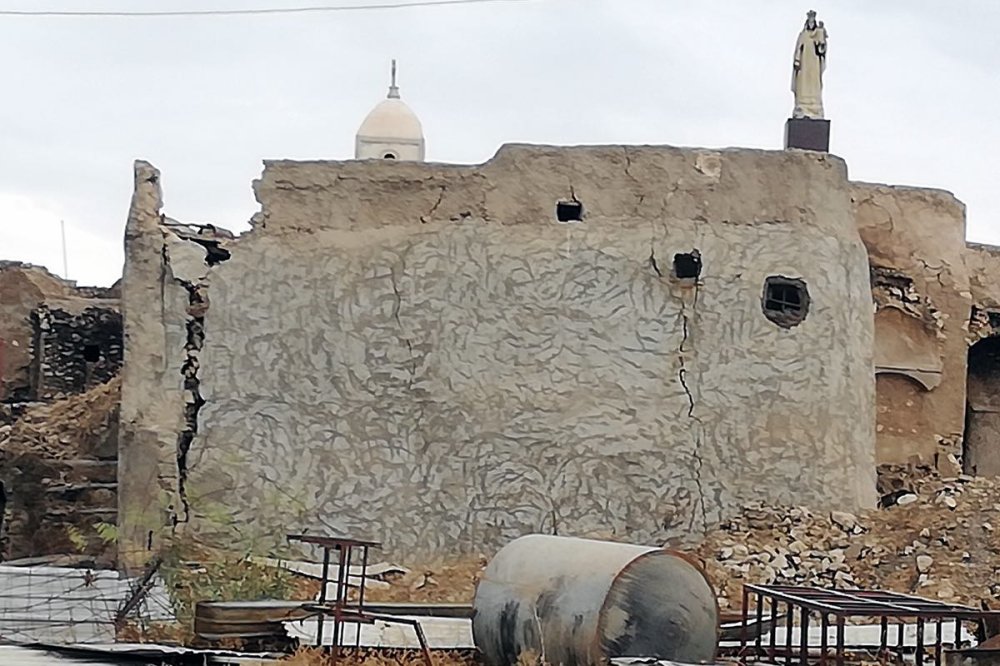 Muro diroccato alle cui spalle emerge una statua della Madonna