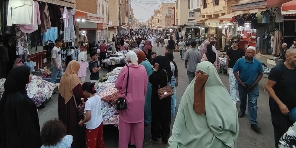 Strada affollata con bancarelle di abiti in una città del Marocco