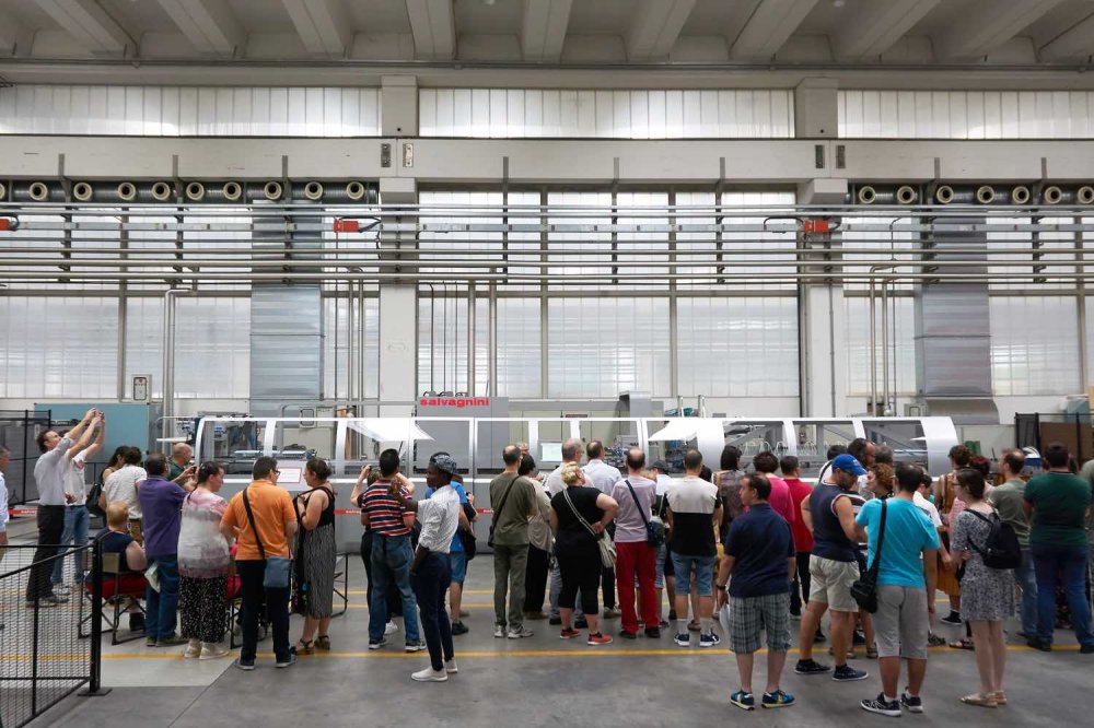 Lungo macchinario circondaoto dai soci della cooperativa sociale