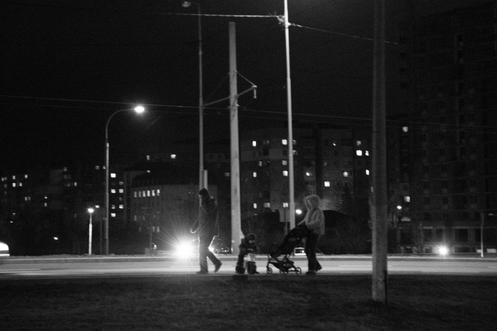 Famiglia con passeggino sulla strada a Leopoli di notte